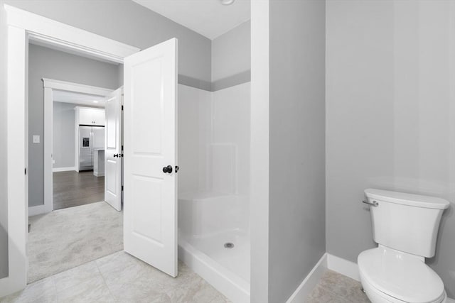 full bathroom featuring a stall shower, toilet, and baseboards