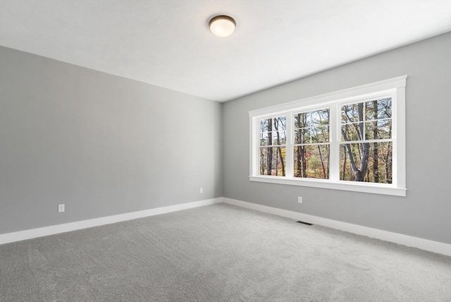 spare room with carpet floors, visible vents, and baseboards