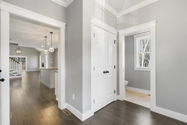 corridor with a notable chandelier, dark wood-style flooring, baseboards, ornamental molding, and stairway