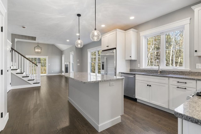 kitchen with stainless steel appliances, dark wood-type flooring, a sink, white cabinetry, and light stone countertops