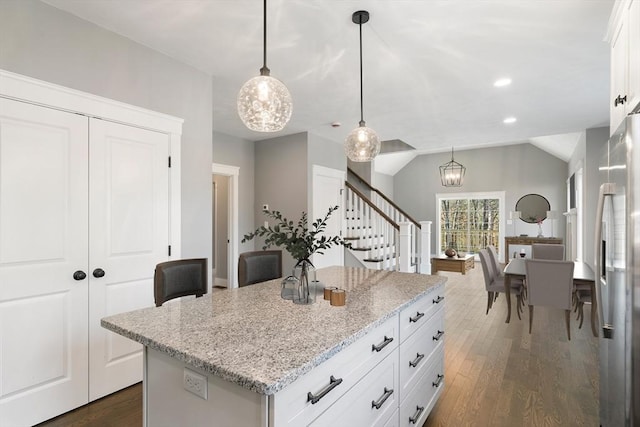 kitchen featuring light stone counters, dark wood-style flooring, lofted ceiling, a kitchen island, and stainless steel fridge with ice dispenser