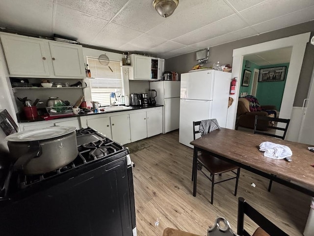 40 Freeman St, Framingham, MA 01702 - kitchen featuring freestanding refrigerator, a paneled ceiling, black gas stove, white cabinets, and light wood-style floors