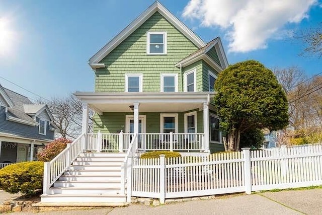 view of front of house with a porch, stairway, and a fenced front yard