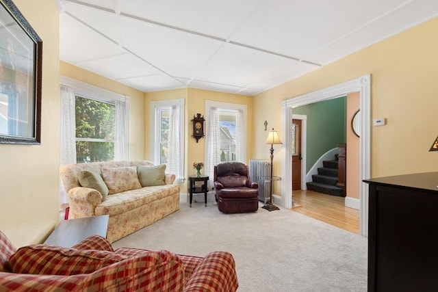 living area with stairway, radiator heating unit, and carpet flooring