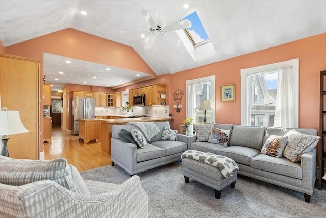 living room featuring recessed lighting, ceiling fan, lofted ceiling with skylight, and light wood-style flooring