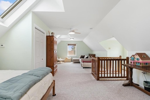 carpeted bedroom featuring a ceiling fan, vaulted ceiling with skylight, and a closet