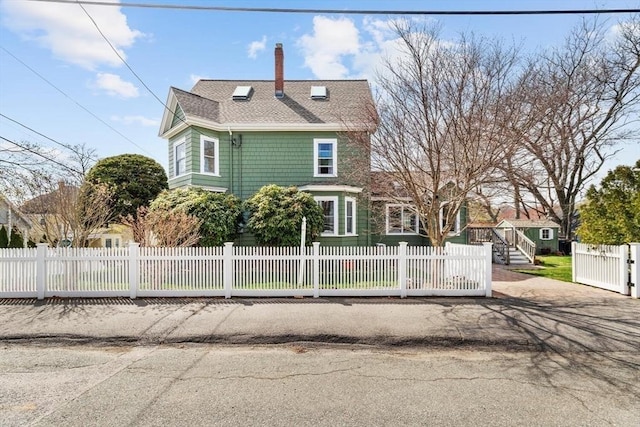 view of front of home featuring a fenced front yard, roof with shingles, and a chimney