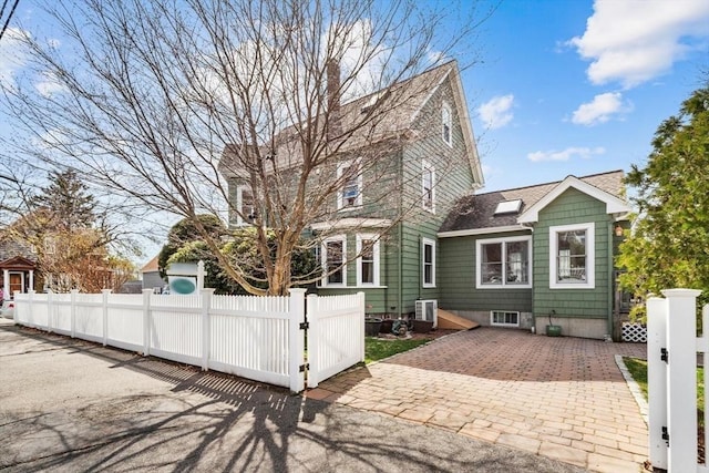 back of house with a shingled roof, a fenced front yard, and a gate