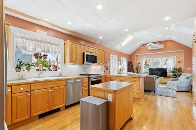kitchen with appliances with stainless steel finishes, a sink, light countertops, a ceiling fan, and a peninsula