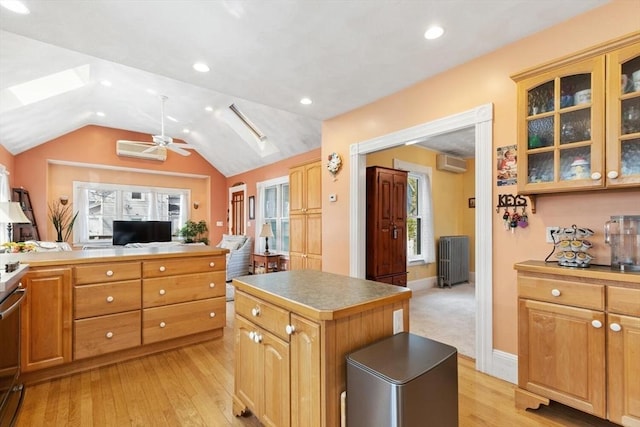 kitchen with a wall unit AC, a ceiling fan, a center island, radiator, and light wood-style flooring