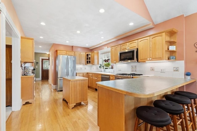 kitchen featuring light brown cabinets, stainless steel appliances, recessed lighting, a peninsula, and decorative backsplash