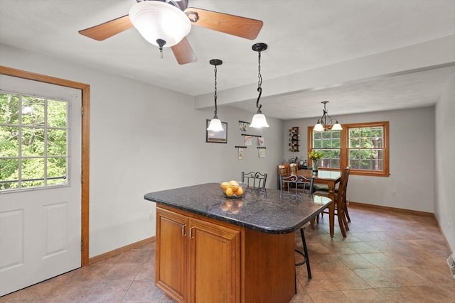 6 2nd Ave, Wilmington, MA 01887 - kitchen featuring a center island, baseboards, a breakfast bar area, hanging light fixtures, and dark stone counters