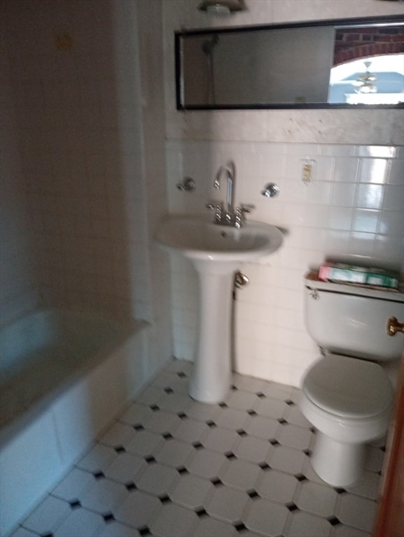 bathroom with toilet and tile walls