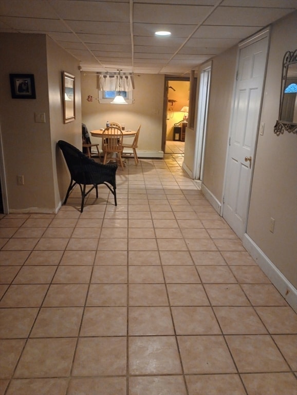 corridor featuring a paneled ceiling and light tile patterned flooring