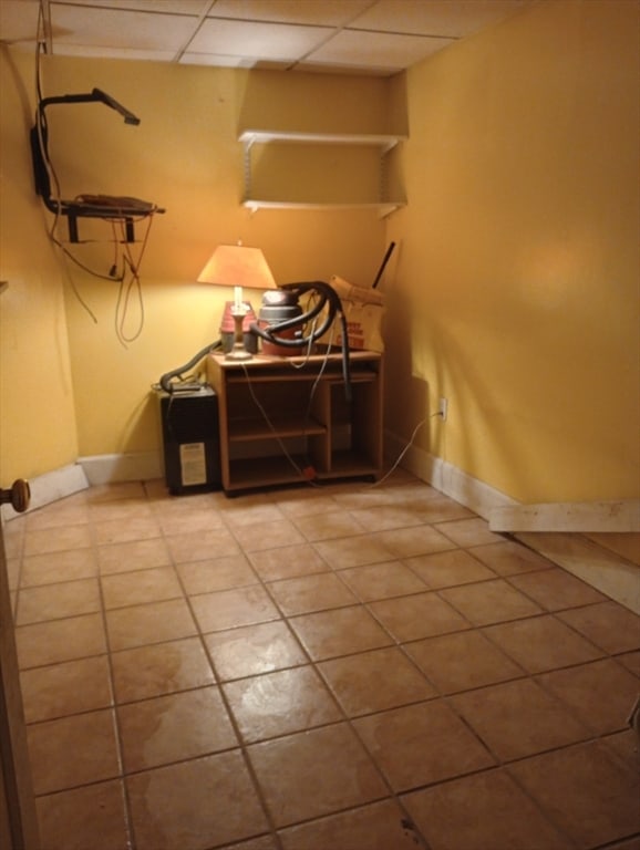 basement featuring a paneled ceiling and tile patterned floors