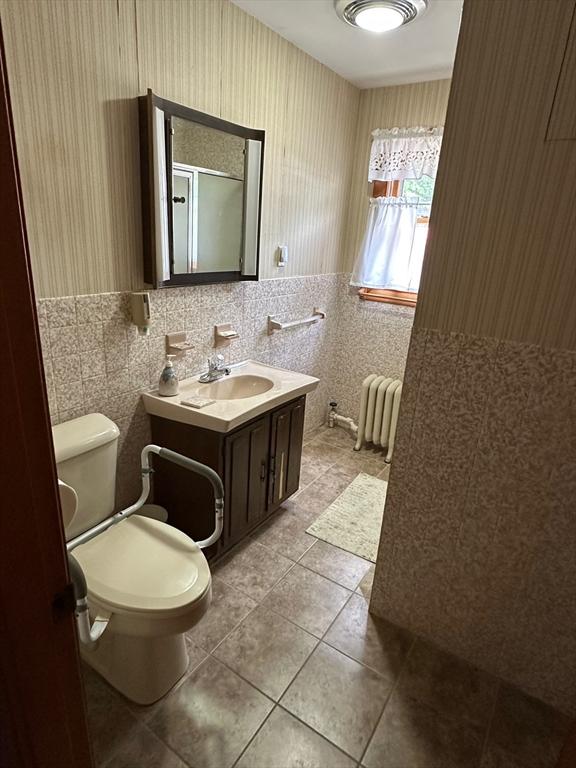 41 Mayland St, Fitchburg, MA 01420 - bathroom featuring radiator, tile patterned floors, toilet, vanity, and tile walls