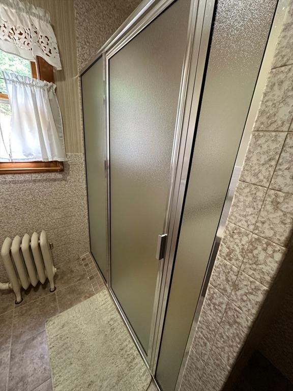 41 Mayland St, Fitchburg, MA 01420 - full bathroom featuring a stall shower, radiator, tile walls, and tile patterned floors