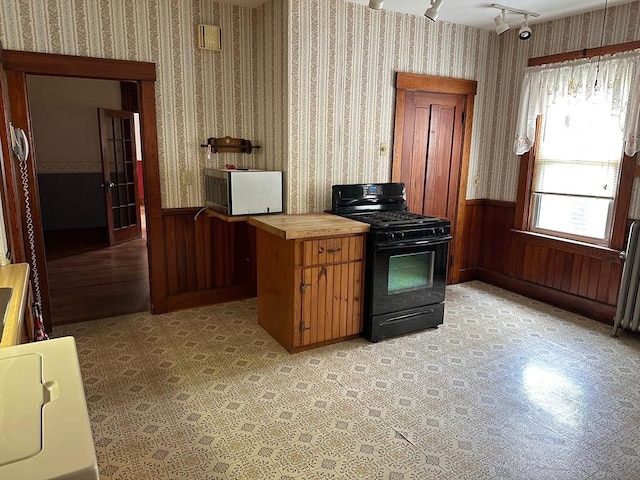 41 Mayland St, Fitchburg, MA 01420 - kitchen with black gas range, stainless steel microwave, wainscoting, wallpapered walls, and wooden walls