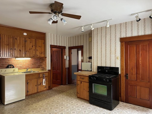 41 Mayland St, Fitchburg, MA 01420 - kitchen with gas stove, washer / clothes dryer, a sink, rail lighting, and wallpapered walls