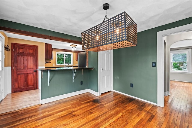 7 Beaver St, Beverly, MA 01915 - kitchen with hardwood / wood-style flooring, dark countertops, a breakfast bar area, baseboards, and a sink