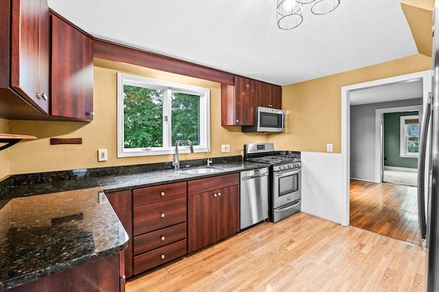 7 Beaver St, Beverly, MA 01915 - kitchen featuring a sink, stainless steel appliances, light wood finished floors, reddish brown cabinets, and dark stone counters