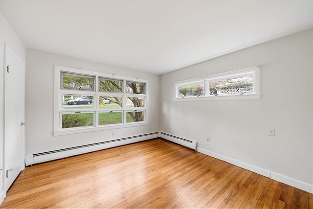 unfurnished room with light wood-style floors, baseboard heating, and baseboards