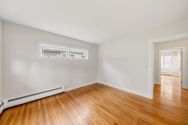 spare room featuring light wood-style flooring, a baseboard radiator, and baseboards
