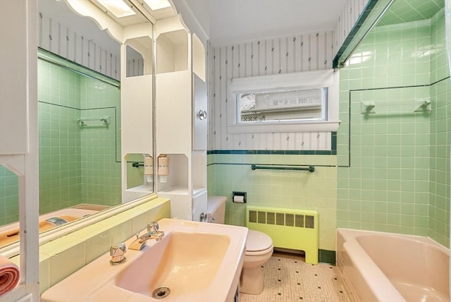 bathroom with radiator, toilet, a sink, and tile walls