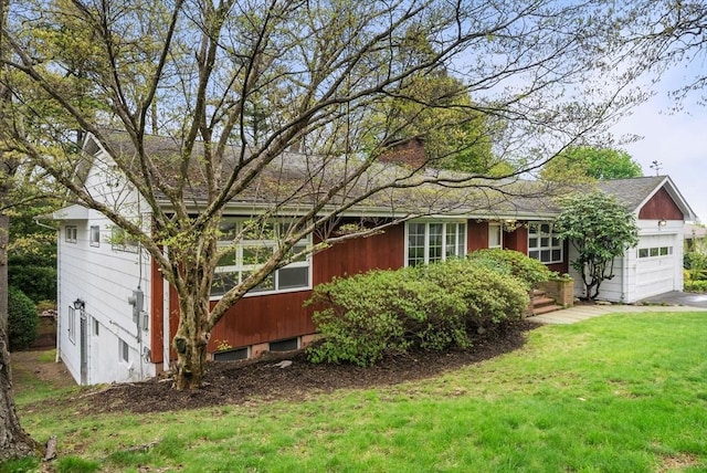 single story home with an attached garage, a front lawn, and a chimney