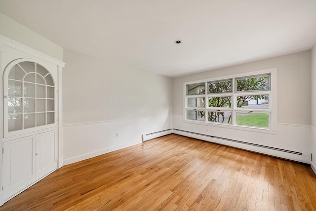 unfurnished room with light wood-type flooring and baseboard heating