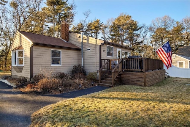 rear view of property with a lawn, a chimney, and a wooden deck