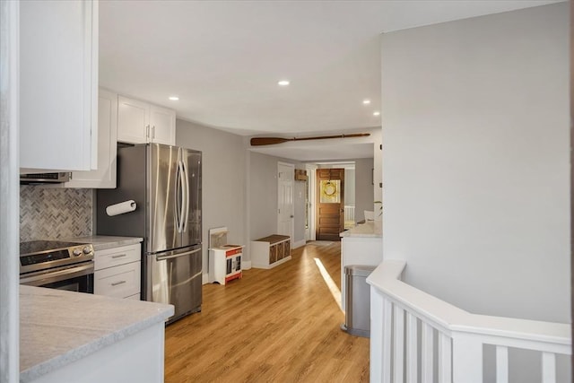 kitchen featuring tasteful backsplash, light wood-style flooring, stainless steel appliances, white cabinetry, and recessed lighting