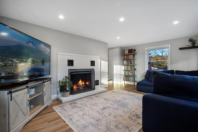 living room featuring recessed lighting, a lit fireplace, and light wood finished floors