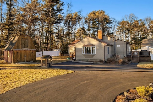 view of front facade featuring an outbuilding, a chimney, and a wooden deck