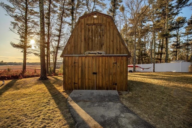 outdoor structure at dusk with an outdoor structure, fence, a storage shed, and a lawn