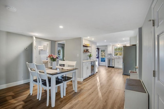 dining area featuring beverage cooler, recessed lighting, light wood-style flooring, and baseboards