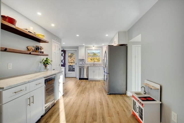 kitchen with white cabinets, light wood-type flooring, wine cooler, and stainless steel appliances