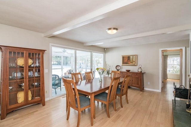 dining area featuring beamed ceiling, light wood-style flooring, and baseboards