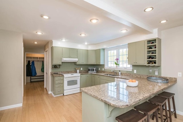 kitchen with white electric stove, green cabinets, a sink, a peninsula, and under cabinet range hood