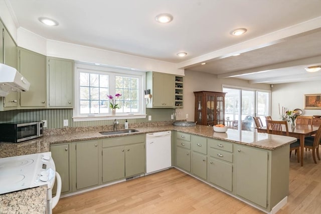 kitchen with white appliances, green cabinetry, a sink, and a peninsula