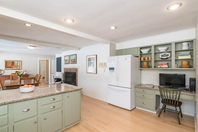 kitchen featuring light stone countertops, white fridge with ice dispenser, light wood finished floors, and green cabinetry