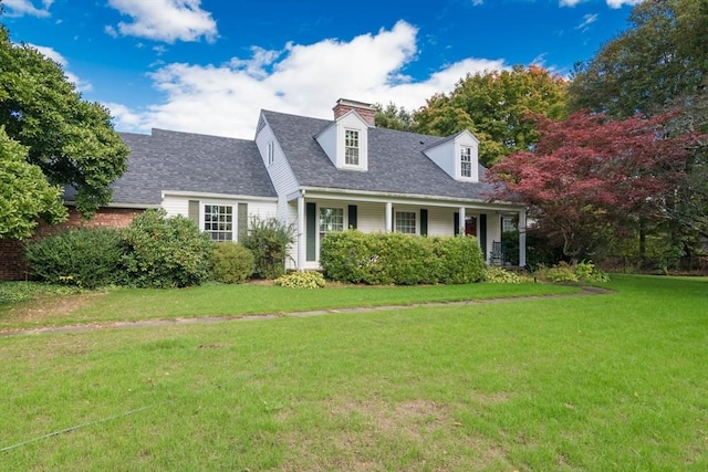 cape cod house with a chimney, roof with shingles, and a front yard