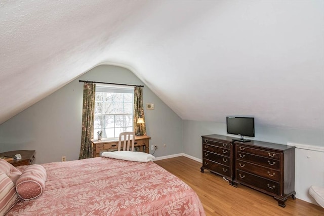 bedroom with lofted ceiling, baseboards, and light wood-style floors