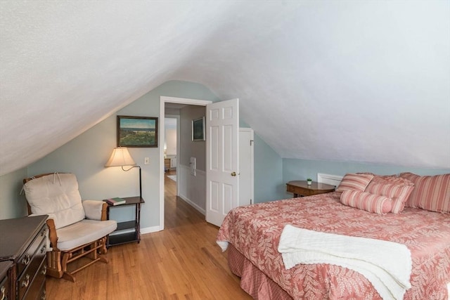 bedroom featuring vaulted ceiling, light wood finished floors, and baseboards