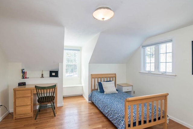 bedroom featuring lofted ceiling, light wood-style flooring, and baseboards