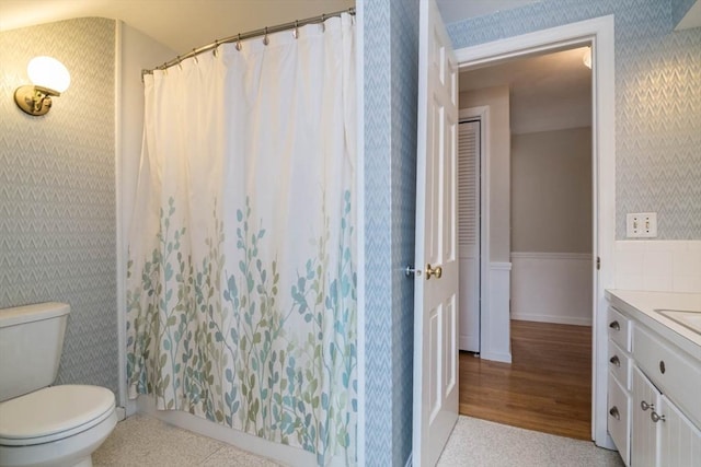 bathroom with a shower with shower curtain, toilet, vanity, wood finished floors, and wallpapered walls