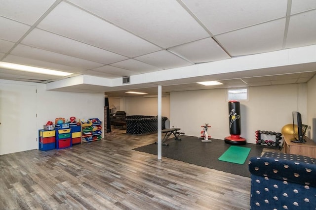 workout area with a drop ceiling, wood finished floors, and visible vents