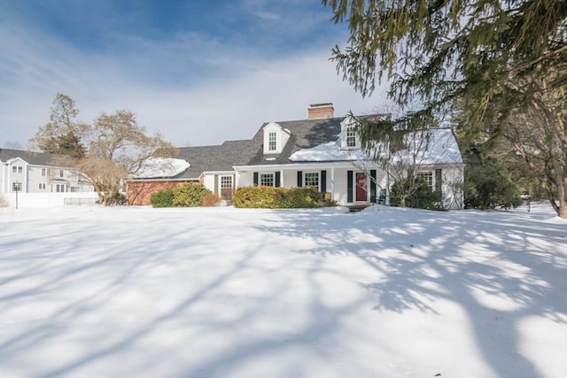 cape cod-style house featuring a chimney and fence