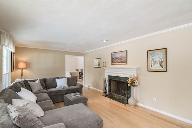 living area with light wood-type flooring, baseboards, ornamental molding, and a high end fireplace