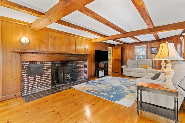 living room with hardwood / wood-style flooring, a fireplace, beamed ceiling, and wood walls